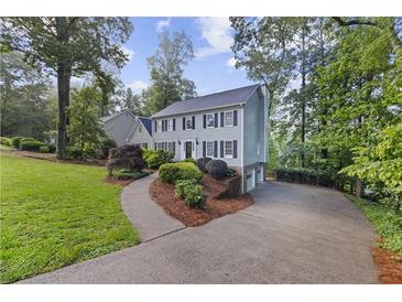 Charming two-story home with a landscaped yard and a curved driveway nestled among mature trees at 4468 Windsor Oaks Dr, Marietta, GA 30066