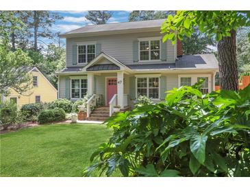 Charming two-story home with well-manicured lawn, pink front door, and beautiful landscaping at 47 Roseclair Se Dr, Atlanta, GA 30317