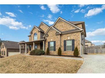 Charming two-story brick home with a covered front porch and well-maintained landscaping at 3823 Dragon Fly Ln, Loganville, GA 30052