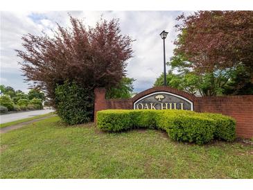 Landscaped Oak Hill community sign with brick base and lush green foliage on a cloudy day at 40 Oak Hill Dr, Covington, GA 30016