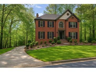 Beautiful brick home featuring mature landscaping, a manicured lawn, and a long driveway leading up to the house at 421 Congress Pkwy, Lawrenceville, GA 30044