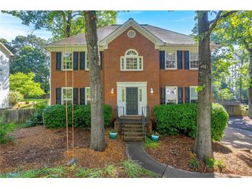 Charming two-story brick home with black shutters and manicured landscaping at 2151 Hamstead Ct, Suwanee, GA 30024