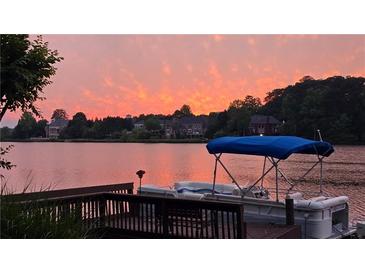Beautiful waterfront view at sunset featuring a boat docked at the pier, perfect for serene living at 3800 Schooner Rdg, Alpharetta, GA 30005