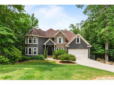 Charming two-story home with stone accents, attached garage, lush lawn and mature trees at 2990 Hearthstone Dr, Cumming, GA 30041