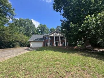 Two-story brick home with white columns, inviting entrance, and lush surrounding greenery at 2000 Brickton Sta, Buford, GA 30518