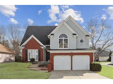 Charming two-story home with a brick and gray exterior, well-manicured lawn, and a two-car garage at 2058 Drogheda Ln, Marietta, GA 30066