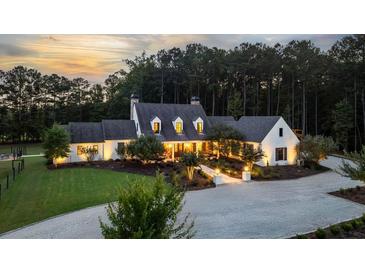 Stunning country home featuring manicured landscaping and a circular driveway at sunset at 7255 Old Rico Rd, Chattahoochee Hills, GA 30268