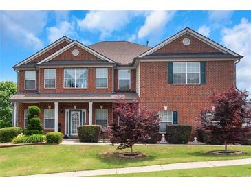 Beautiful two-story brick home featuring a covered front porch and manicured landscaping at 1104 Stepping Stone Ln, Conyers, GA 30012