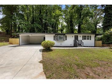 Charming single-story home with white brick, dark trim, front yard, and open carport at 4720 Shoshonee Trl, College Park, GA 30349