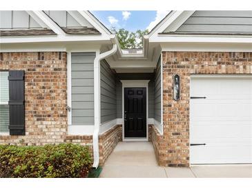 Charming brick home with a black front door, gray siding, and a well-maintained yard and white garage door at 131 Prominence Ct, Canton, GA 30114