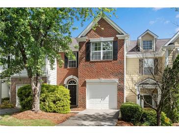 Charming two-story brick townhome with attached garage and manicured landscaping at 208 Magnolia Leaf Dr, Woodstock, GA 30188