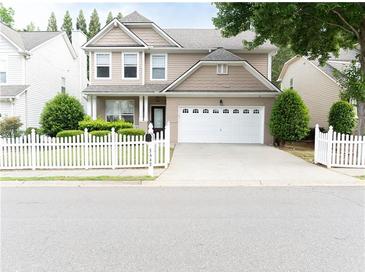 Charming two-story home features a well-manicured lawn, white picket fence, and attached two-car garage at 3442 Old Towne Ln, Cumming, GA 30040