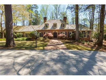 Charming brick home featuring a beautiful front lawn, mature trees, and a welcoming entrance at 9995 Huntcliff Trce, Atlanta, GA 30350