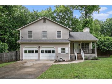 Charming two-story home with a two-car garage and inviting front porch nestled amongst the trees at 1888 Kelvin Dr, Lawrenceville, GA 30043