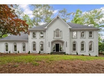 Elegant white home featuring symmetrical design, arched windows, and professionally landscaped front yard at 605 Buttercup Trce, Johns Creek, GA 30022