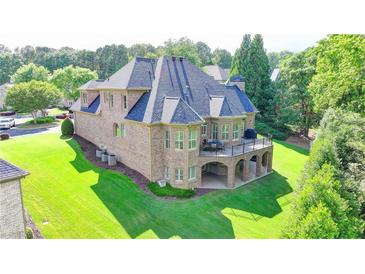 Stunning brick home featuring a large balcony overlooking a lush green lawn and mature trees at 8340 Royal Melbourne Way, Duluth, GA 30097