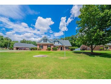 Inviting brick home featuring a beautifully manicured front yard under a partly cloudy sky at 1480 Holly Brook Rd, Snellville, GA 30078
