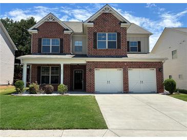 Two-story brick home featuring an attached two-car garage, well-maintained lawn, and an inviting covered front porch at 1777 Weatherbrook Cir, Lawrenceville, GA 30043