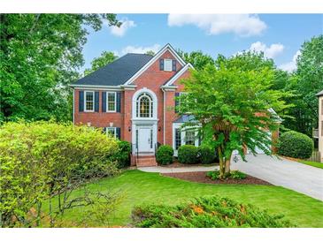 Beautiful two-story brick home with manicured lawn, lush trees, and charming curb appeal at 4910 Aldbury Ln, Suwanee, GA 30024