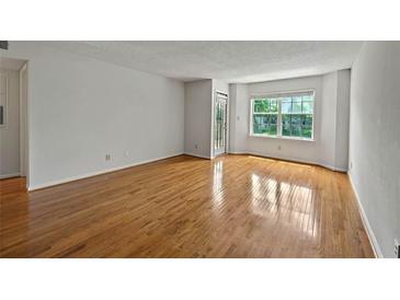 Bright, open living room with gleaming hardwood floors and large window at 4106 Chastain Park Ne Ct, Atlanta, GA 30342