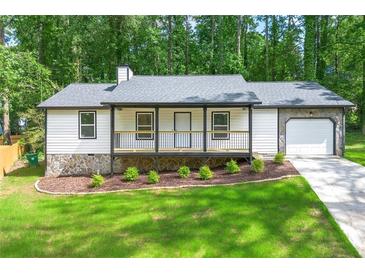 Charming renovated home featuring a welcoming porch and attached garage, all nestled on a lush green lot at 4043 Chedworth Way, Stone Mountain, GA 30083