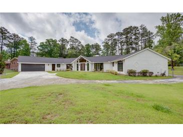 Stunning white brick home featuring a modern design, lush lawn, and a spacious driveway leading to an attached garage at 4700 Cascade Sw Rd, Atlanta, GA 30331