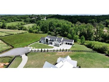 Expansive aerial view of modern farmhouse estate with lush green pastures and a long driveway at 5160 Howard Rd, Cumming, GA 30040