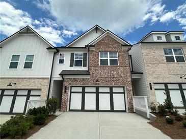 Charming townhome with brick facade, white siding, and a two-car garage at 257 Depot Landing Rd # 39, Auburn, GA 30011