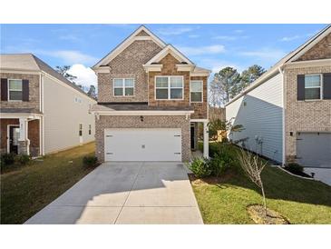 Charming two-story home featuring a brick facade and a two-car garage, set against a bright sky at 853 Bentley Drive Dr, Fairburn, GA 30213