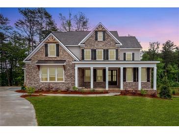 Charming two-story brick home with a welcoming front porch and meticulously manicured lawn at 1073 Sweet Mia Ln, Powder Springs, GA 30127