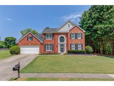 Charming brick home featuring a well-manicured lawn, two-car garage, and beautiful landscaping at 1370 Stoney Field Place, Lawrenceville, GA 30043