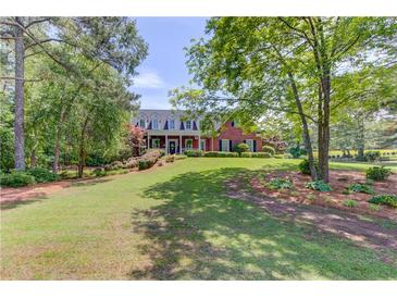 Beautiful brick home with a manicured lawn and mature trees providing shade and curb appeal at 1292 Green Turf Dr, Snellville, GA 30078