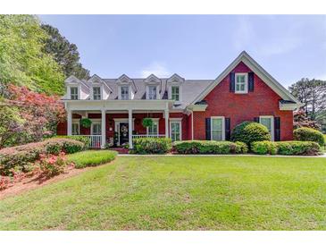 Charming brick home with a large front porch, lush landscaping, and a well-manicured lawn at 1292 Green Turf Dr, Snellville, GA 30078