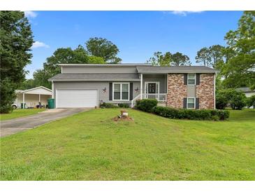 Charming two-story home with manicured lawn, attached garage, and inviting front porch at 1903 Lochlomand Se Ln, Smyrna, GA 30080