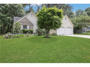 Charming home featuring lush green lawn, two-car garage, beautiful landscaping with a mix of trees and flowering plants at 3001 Garland Sw Dr, Marietta, GA 30008