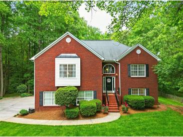 Charming two-story brick home with a well-manicured lawn, lush landscaping, and a welcoming front entrance at 827 Pinehurst Dr, Woodstock, GA 30188