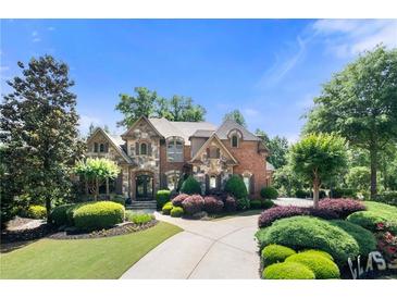Stunning brick and stone home with manicured landscaping and a circular driveway at 8340 Colonial Pl, Duluth, GA 30097