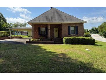 Charming single-story brick home with a manicured lawn, mature landscaping, and covered carport at 871 Malcom Se St, Conyers, GA 30012