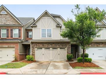 Charming townhome featuring a stone and neutral siding exterior, a two-car garage, and manicured landscaping at 1630 Marsanne Nw Ter # 27, Kennesaw, GA 30152