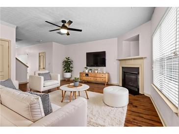 Bright living room with modern ceiling fan, fireplace, and plush white furniture at 867 Crested Hawk Trl, Sugar Hill, GA 30518