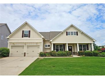 Charming, light beige home featuring a two-car garage, manicured lawn, and colorful flowerbeds at 4024 Broadmoor Sw Ct, Austell, GA 30106