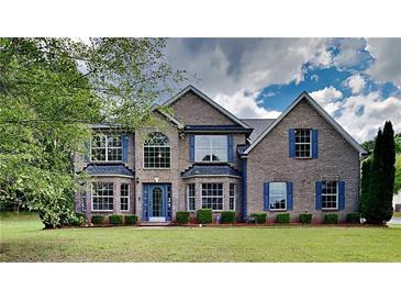 Elegant brick home featuring a lush lawn, beautiful windows and blue shutters at 4706 Derby Loop, Fairburn, GA 30213