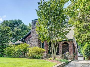 Charming brick home with stone chimney, lush landscaping, and covered arched entryway offering curb appeal at 1356 Emory Ne Rd, Atlanta, GA 30306
