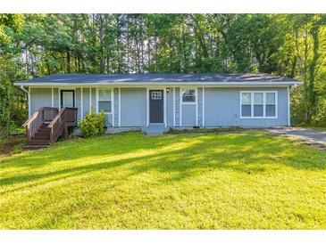 Charming single-story home featuring a well-manicured lawn, inviting entryway, and a serene, tree-lined backdrop at 4650 Big Valley Ct, Stone Mountain, GA 30083