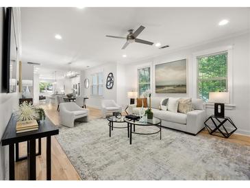 Bright, open-concept living room with modern furnishings and hardwood floors, seamlessly connecting to the kitchen and dining area at 770 Ormewood Se Ave, Atlanta, GA 30312