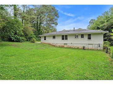 Spacious backyard features a well-maintained lawn and the home's exterior with painted white brick at 2406 Tilson Rd, Decatur, GA 30032