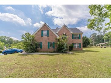 A well-kept brick two story home has a manicured lawn and green shutters at 4023 Port Springs Trl, Snellville, GA 30039