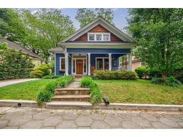 Charming blue home features a welcoming front porch, a wooden front door, and lush landscaping at 549 Atwood Sw St, Atlanta, GA 30310