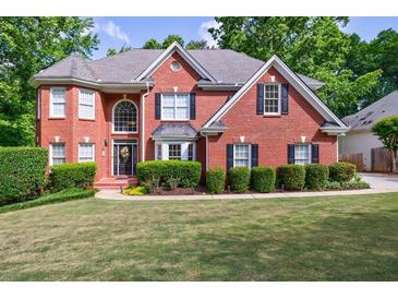 Charming two-story brick home featuring a well-manicured lawn and mature trees at 265 Dogwood Walk Ln, Norcross, GA 30071