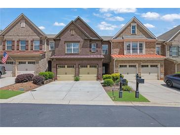 Brick townhome featuring an attached two-car garage, manicured landscaping, and a driveway perfect for multiple cars at 1929 Brightleaf Way, Marietta, GA 30060
